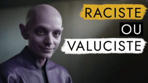 Homme chauve dans une veste violette souriant, avec des superpositions de texte indiquant « racisme ou valuciste » en jaune et blanc sur fond noir.