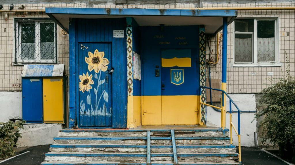 Entrée de l'ancien bâtiment avec des portes peintes en bleu et jaune vif avec un motif tournesol et symbolisant le soutien à l'Ukraine pendant la guerre contre la Russie.